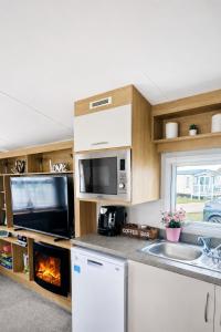 a kitchen with a stove top oven next to a sink at Magic Caravan Camber Sands 221 in Camber