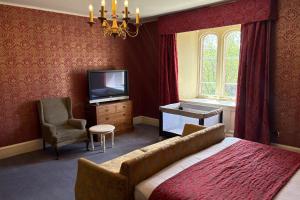 a bedroom with a bed and a tv and a chair at Ruthin Castle Hotel and Spa in Ruthin