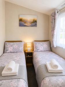two beds in a small room with towels at Magic Caravan Camber Sands 221 in Camber +1 photo