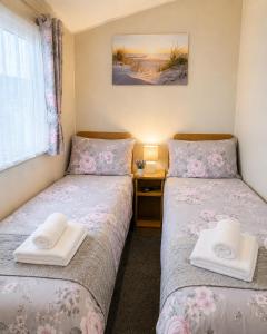 two twin beds in a room with a window at Magic Caravan Camber Sands 221 in Camber