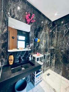 a black bathroom with a sink and a shower at Prestige Stay a Perla Méditerranée avec Picine au Centre Mdiq in M'diq