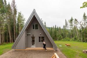 a person standing in front of a house with a dog at Canadian Classic - Spa - Sauna - Fire - Forest in Val-David +49 photos