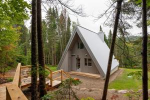 a tiny house in the woods with a porch at Canadian Classic - Spa - Sauna - Fire - Forest in Val-David