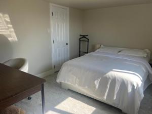 a bedroom with a white bed and a table at ocean view two bedroom suite in Oak Bay