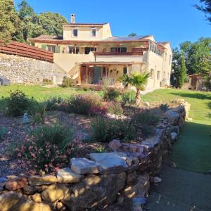 a house with a stone wall in front of a yard at Flassans Gites &Spa in Flassans-sur-Issole
