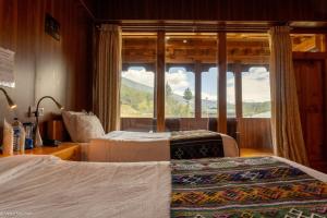 two beds in a room with a large window at Valley Resort in Jakar