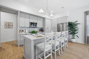 a kitchen with white cabinets and a kitchen island with stools at Spacious 3BR - Pool - Beach Nearby in Pass Christian