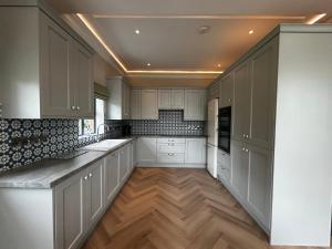a kitchen with white cabinets and a wooden floor at Teach na Radharc in Raheen +7 photos
