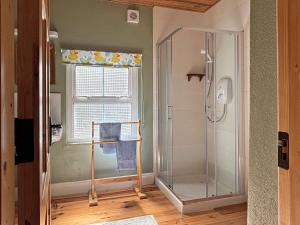 a bathroom with a shower and a window with a shower curtain at Cottage 507 - Renvyle in Renvyle