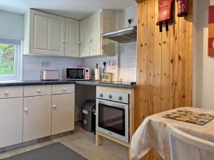 a kitchen with white cabinets and a stove top oven at Cottage 507 - Renvyle in Renvyle +28 photos