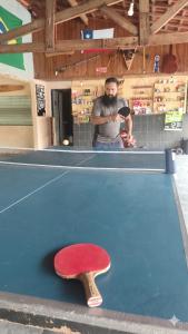 a man standing next to a pool table with a red paddle at Apartamento no Camping Mairipora in Mairiporã