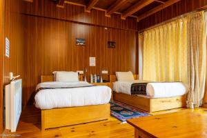 two beds in a room with wood paneling at Valley Resort in Jakar