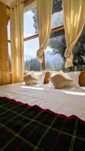 a bed in a room with a large window at Jibhi Dreams in Jibhi