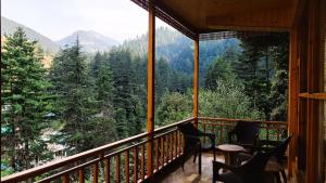 a room with a balcony with a view of the mountains at Jibhi Dreams in Jibhi