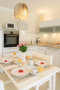 a white kitchen with a table with plates and flowers at Mein-Zingst-Urlaub in Zingst