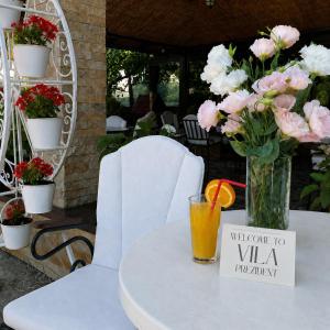 a table with a vase of flowers and a drink at Vila Prezident in Sremski Karlovci