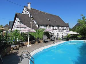 a house with a swimming pool in front of a building at Sabershausen Landhof Sonne in Sabershausen