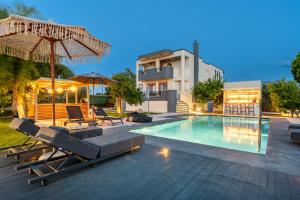 a swimming pool with lounge chairs and an umbrella at The Infinities - Premium Villa Alexandros in Kos