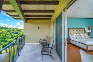 a bedroom with a bed and chairs on a balcony at Las Terrazas 7 Peninsula Papagayo in Nacascolo