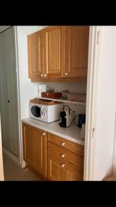 a kitchen with wooden cabinets and a microwave on a counter at Studio pied de piste Pelvoux 2 in Vars
