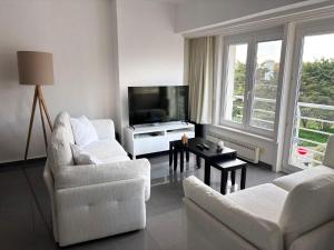 a living room with two chairs and a flat screen tv at Appartemment familial à Westende in Westende-Bad