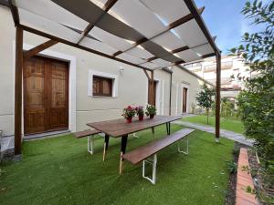a patio with a wooden table and benches at Casale Don Minzoni in Misterbianco