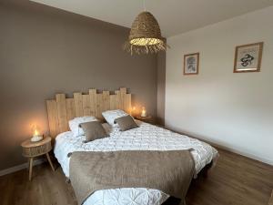 a bedroom with a large bed and a chandelier at Le Cottage Bigouden in Combrit