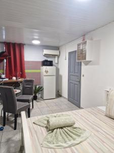 a room with a kitchen and a table with chairs and a refrigerator at Cayenne MIRZA 2 Confort T2 in Cayenne