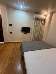 a bedroom with a bed and a flat screen tv at The Courtyard Stay in Patna