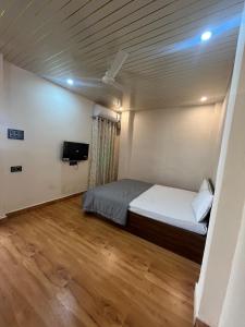a room with a bed and a television in it at The Courtyard Stay in Patna