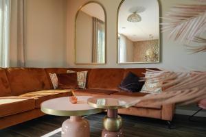 a living room with a brown couch and two mirrors at Parc La Dune Marrakesh Lodge in Warmenhuizen