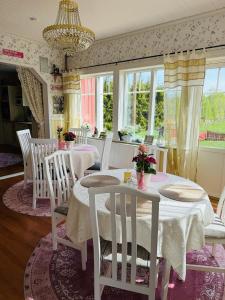 a dining room with white tables and chairs and windows at Slätterne Gård B&B in Sandviken