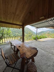 a wooden picnic table and a chair under a roof at Chacha's House in Sapa