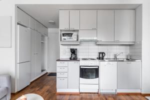 a white kitchen with white cabinets and appliances at Central Studio I by Elys Collection in Rovaniemi