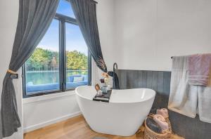 ein Badezimmer mit einer weißen Badewanne vor einem Fenster in der Unterkunft Tiny House on a Waterfall at Private Tiny Lake in Brackney