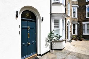 a blue door on a white house with a potted plant at Kent House in Ramsgate