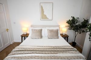a bedroom with a large white bed with two lamps at Kent House in Ramsgate