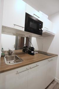 a kitchen with a sink and a microwave on a shelf at Top Studio SV1020 Centre Vincennes 20M2 in Vincennes