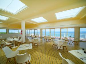 a dining room with tables and chairs and windows at Hotel Club Perla in Casalabate