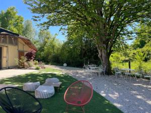 a yard with chairs and tables and a tree at Domaine de cézille-Appart hôtel le Moulin du lac "Paul" in Jayat