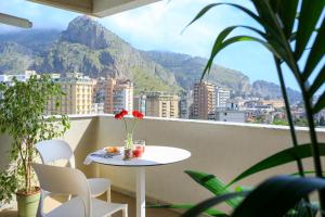 a table and chairs on a balcony with a mountain at Marbela Apartments & Suites in Palermo