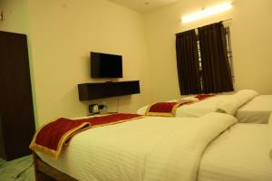 two beds in a room with a tv on the wall at Lumiere Point Yercaud in Yercaud