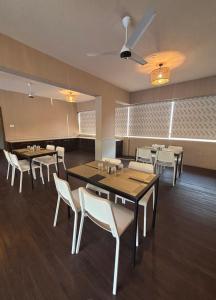 a dining room with tables and white chairs at Amazinn Hotel in Lonavala
