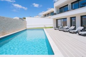a house with a swimming pool and lounge chairs at Eden Villa, with jacuzzi and ocean view in Casal do Cigano