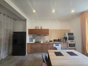a kitchen with a table and a black refrigerator at Cocon des Arènes Nîmes Centre 18 couchages in Nîmes