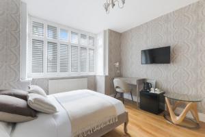a bedroom with a bed and a desk and a tv at Katolondonhaus in Mitcham