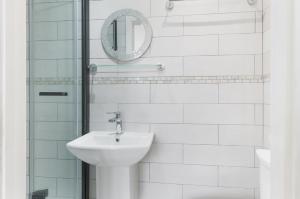 a white bathroom with a sink and a mirror at Katolondonhaus in Mitcham