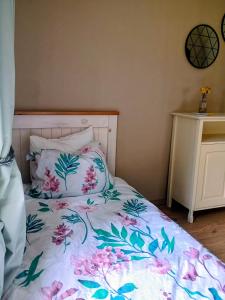 a bed with a white bedspread with pink flowers on it at Heinamaa Lodge with sauna in Lammasküla +5 photos