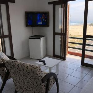 a living room with a couch and a tv and a table at Hotel D'Italia in Arroio do Sal