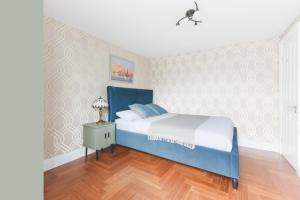 a bedroom with a blue bed and a night stand at Katolondonhaus in Mitcham
